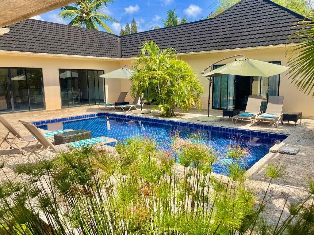 a swimming pool in front of a house at Grand Amber Villa in Diani Beach