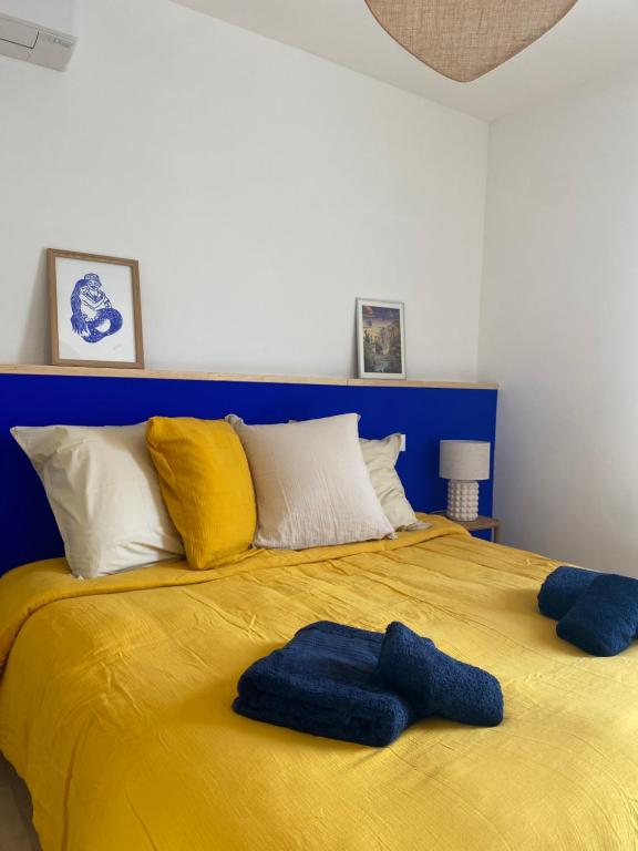 - un grand lit jaune avec 2 oreillers bleus dans l'établissement Le Brassens, à Sète