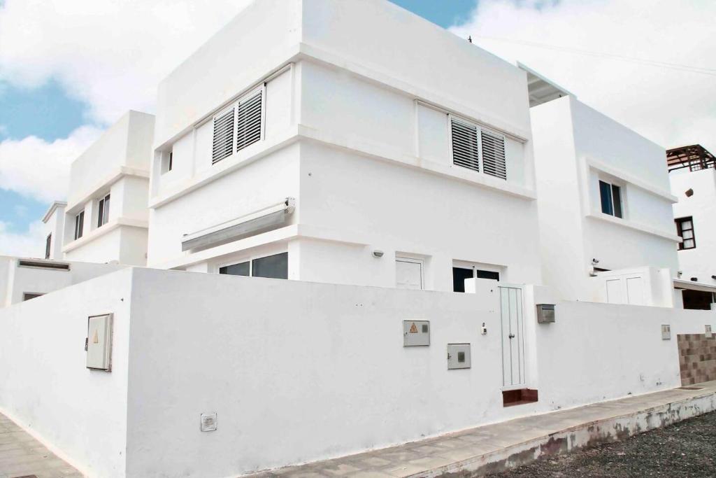 biały budynek apartamentowy z białą ścianą w obiekcie Gran terraza 1 minuto de las piscinas naturales w mieście Punta de Mujeres