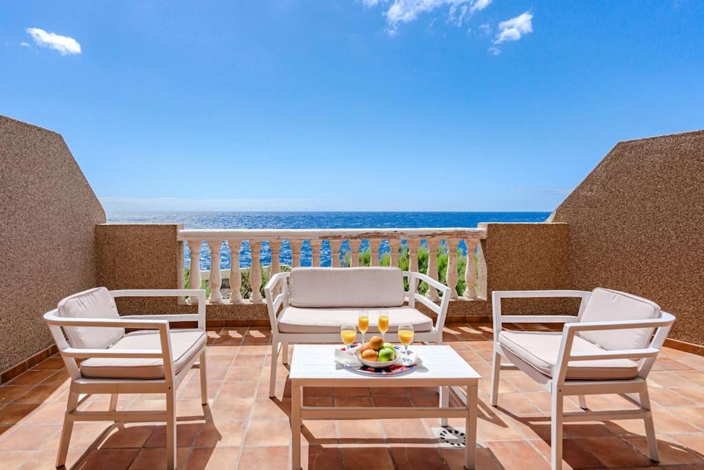 a patio with chairs and a table and the ocean at Seaside Apartment with Spacious Terrace, Pool, and Wi-Fi in Santa Cruz de Tenerife