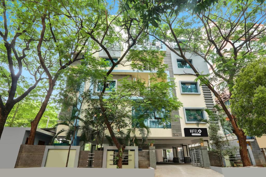 a white building with trees in front of it at Super Hotel O Madhapur VIP Hills in Hyderabad