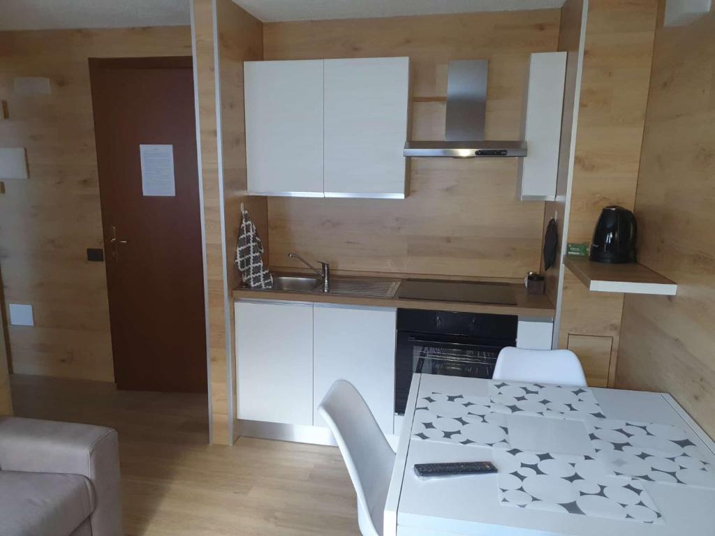 a kitchen with white cabinets and a table and chairs at Alpin House Tonale in Passo del Tonale