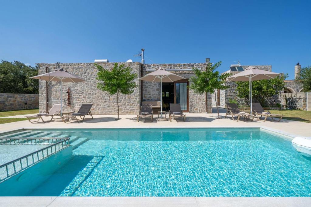 une piscine avec chaises et parasols à côté d'un bâtiment dans l'établissement Villa Liatiko with private pool, à Atsipádhes