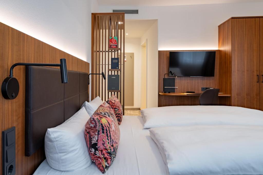 Una habitación de hotel con dos camas y un televisor de pantalla plana. en Hotel Alma Am Anger, en Erfurt