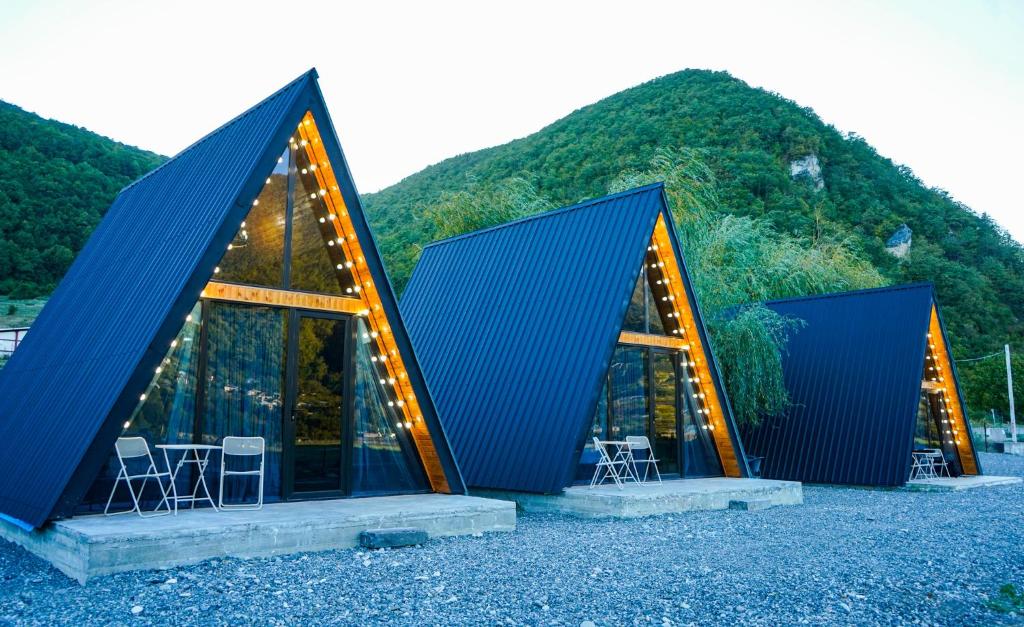two triangular houses with chairs in front of a mountain at Kvabtkari Cottages in Ambrolauri