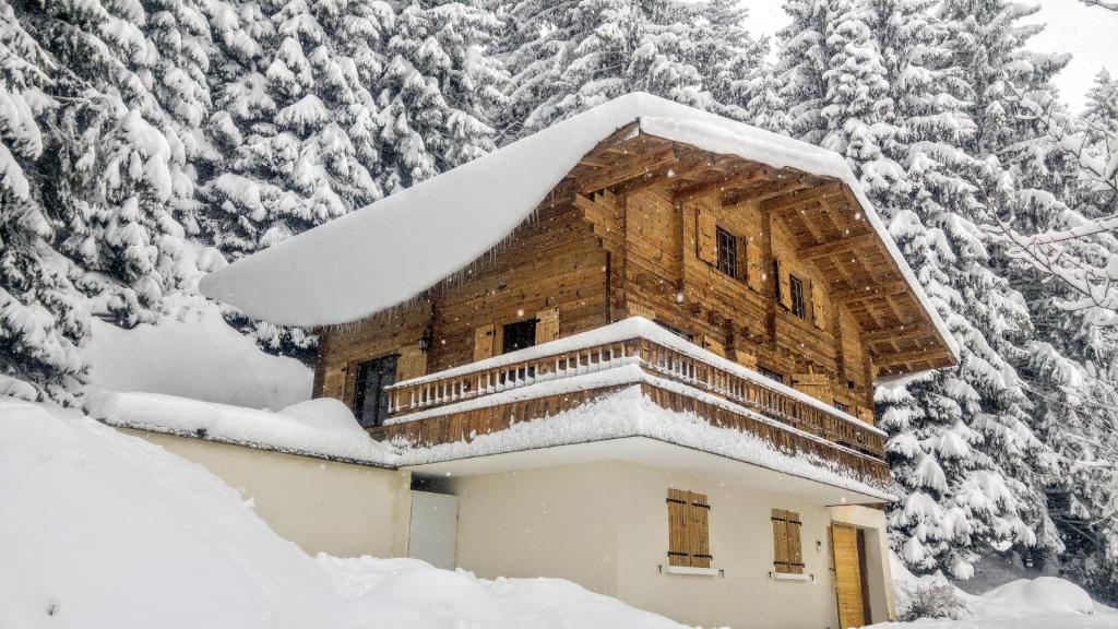 un edificio ricoperto di neve con alberi sullo sfondo di CHALET SPA BELLE VUE 500 m des pistes a Manigod