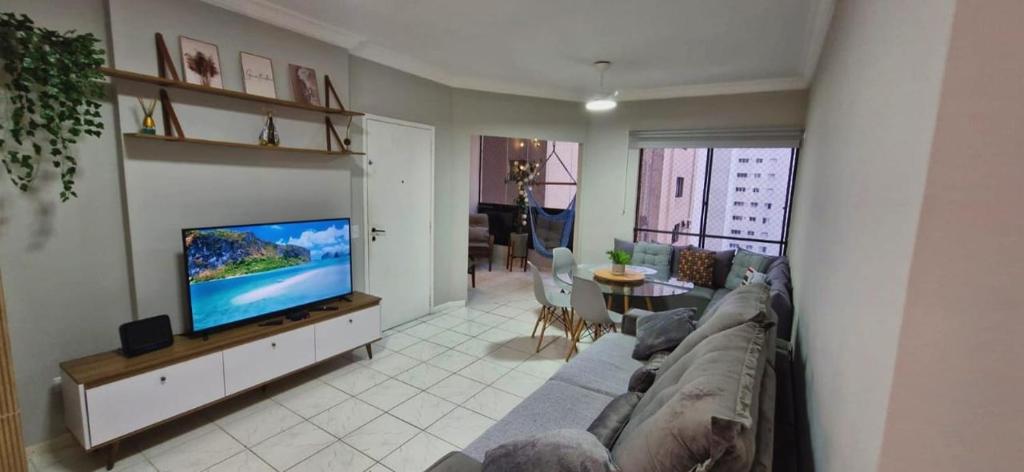 a living room with a couch and a flat screen tv at Apartamento Praia das Pitangueiras - Condomínio Golden Tower in Guarujá