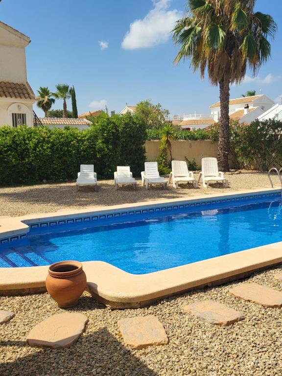 una piscina con sedie e sedie accanto a una casa di Quiet Relaxing 3 bed 3 bath Villa for 8 Camposol Sect D a Mazarrón