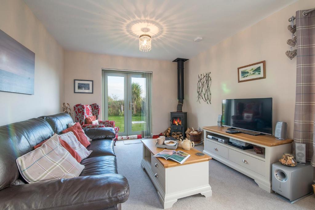 ein Wohnzimmer mit Ledercouch und Fernseher in der Unterkunft Skylark Cottage in Haverfordwest