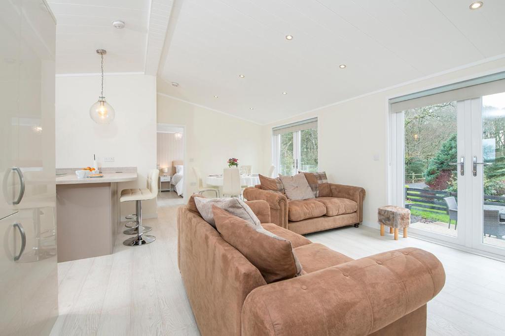 a living room with two brown couches and a kitchen at Hafod Y Coed Lodge in Narberth