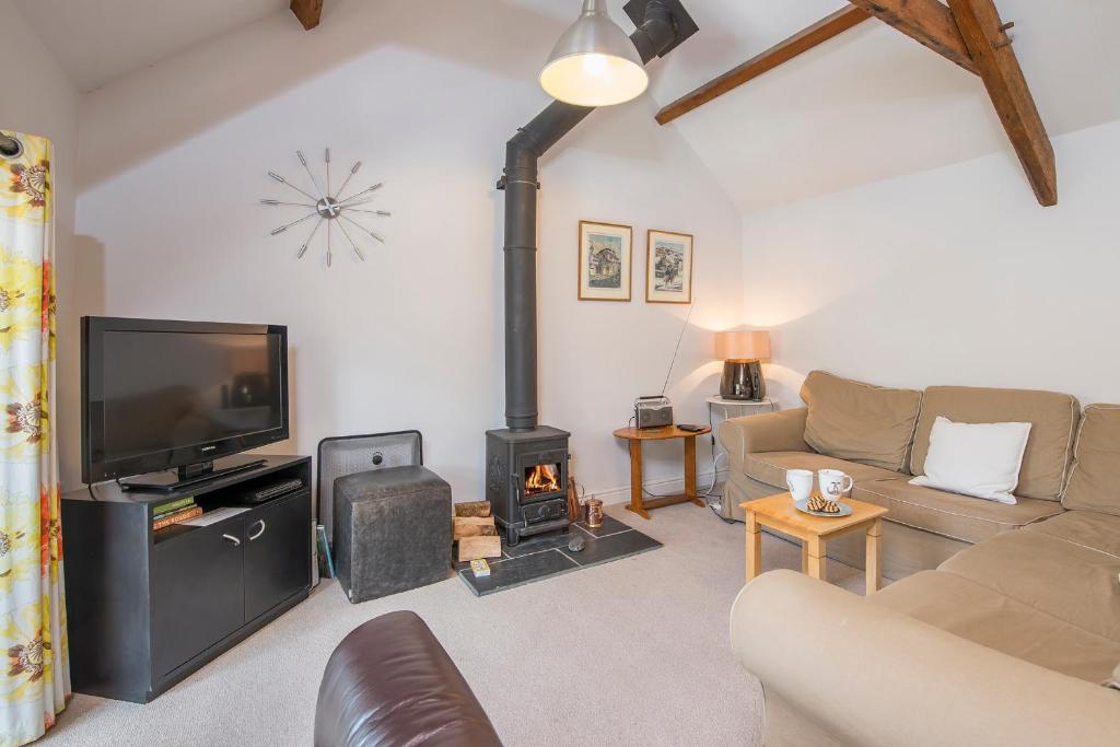 ein Wohnzimmer mit Kamin und Fernseher in der Unterkunft Weavers Cottage in Lampeter-Velfrey