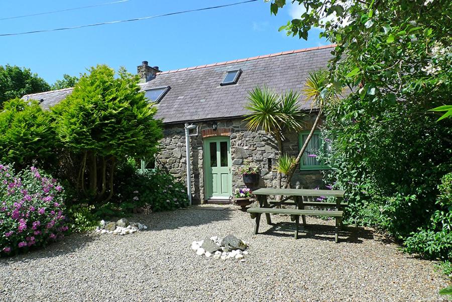 ein Steinhaus mit einer Bank davor in der Unterkunft Honeysuckle Cottage in Solva