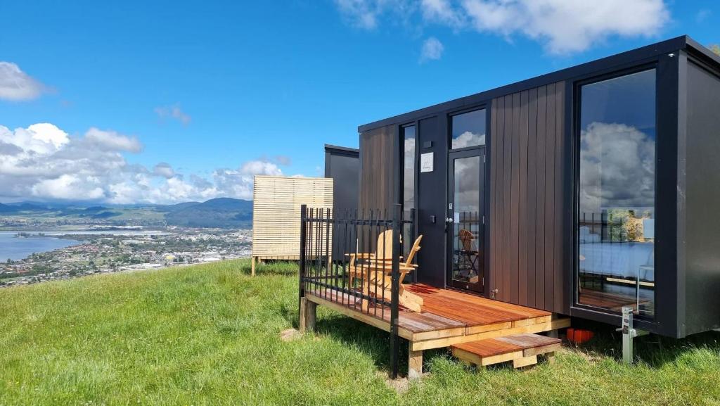 a black tiny house on a hill with a bench at Aorangi Peak Cabins 5 by Tiny Away in Rotorua