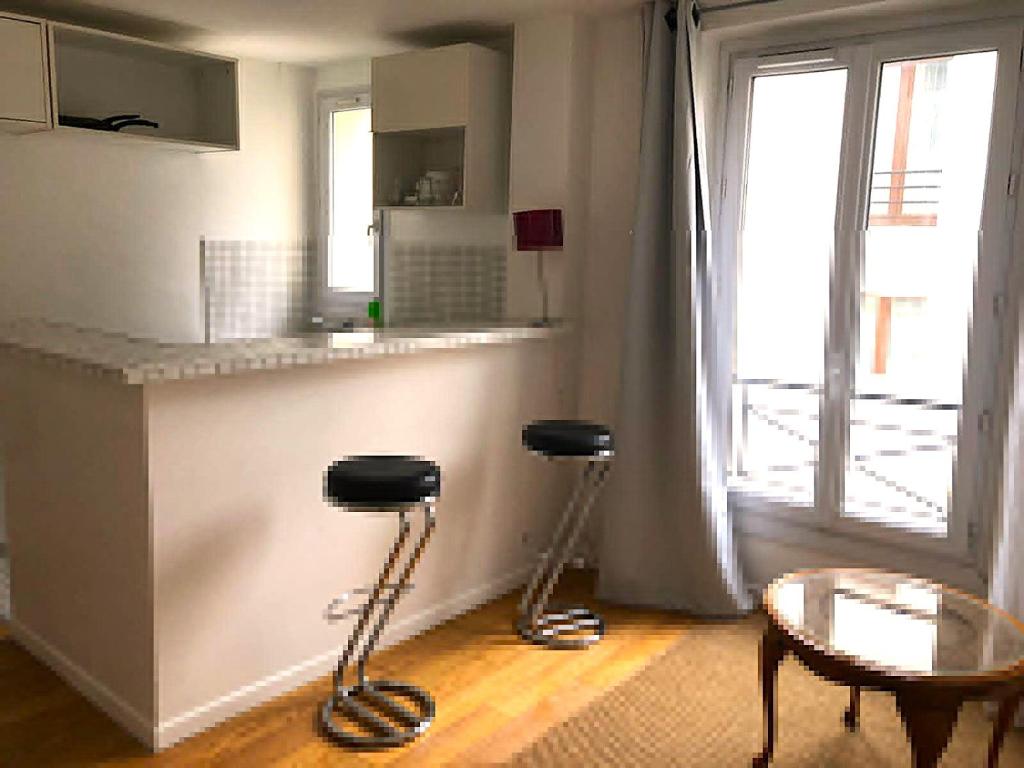 une cuisine avec un comptoir, deux tabourets et une table dans l'établissement Charmant 2 pièces dans IMPASSE FLEURIE, à Paris