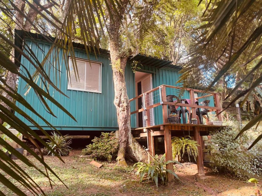 a blue house with a tree in front of it at Container com Deck e Vista I Climatizado e Aconchegante em Curitiba na Natureza in Curitiba