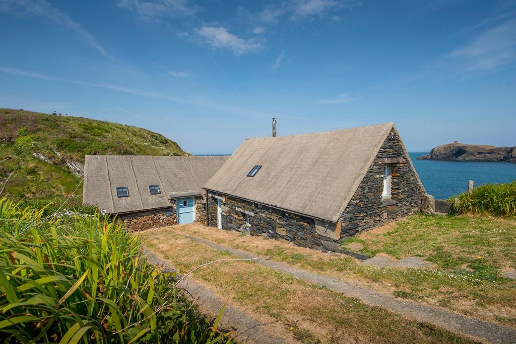 a stone house on a hill next to the ocean at Melin Abereiddy in Haverfordwest