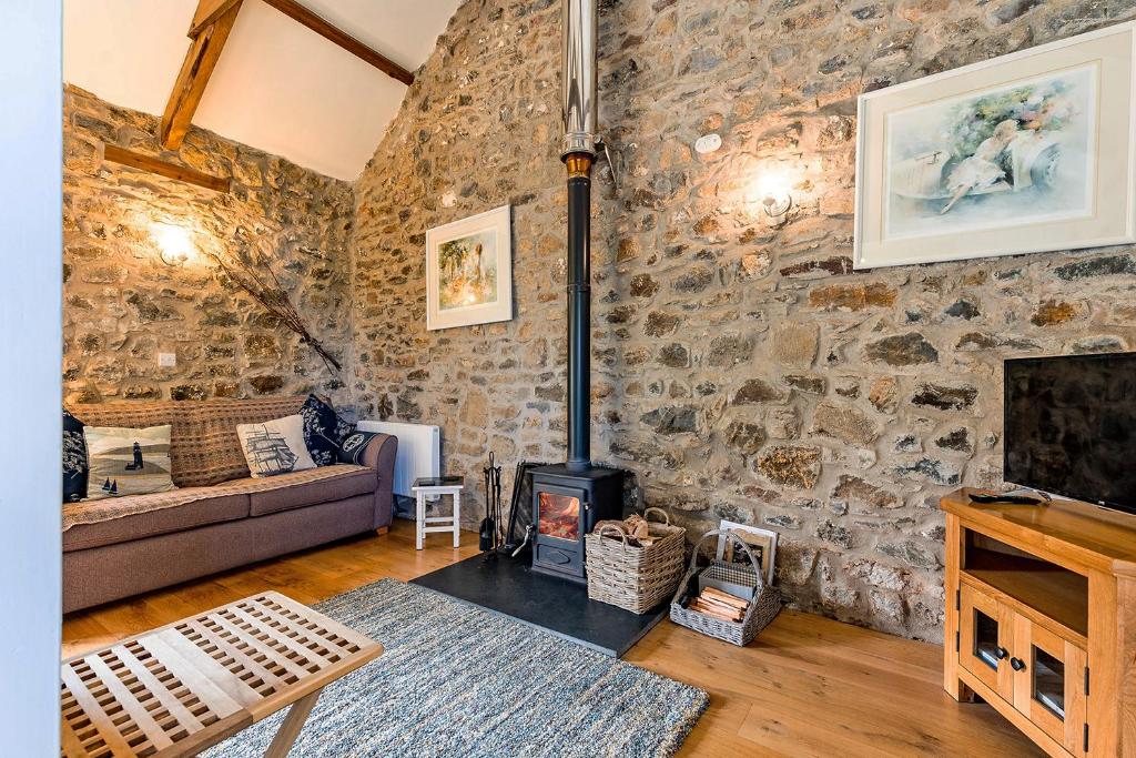 ein Wohnzimmer mit Steinmauer und Holzofen in der Unterkunft Little Rogeston Cottage in Haverfordwest