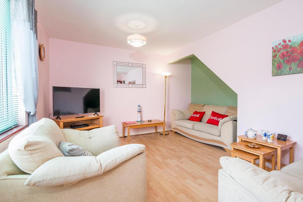 a living room with two white couches and a television at Cwtch Cottage in Haverfordwest