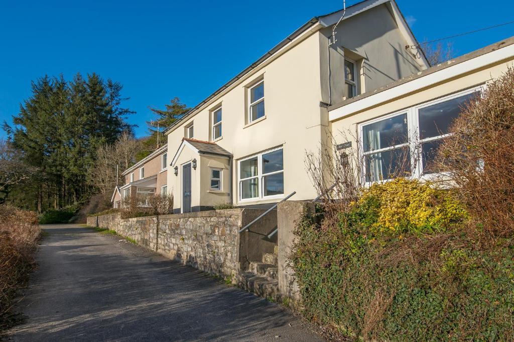 una casa blanca con una pared de piedra y una calle en Upper Mead, en Narberth