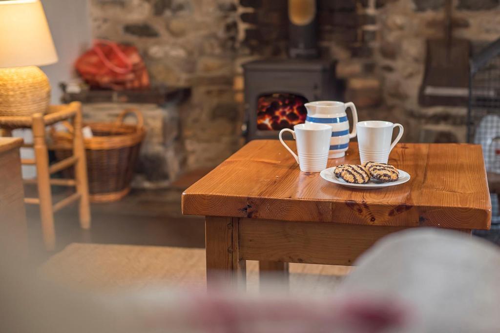een tafel met twee kopjes en een bord koekjes bij Ty Canol in Goodwick