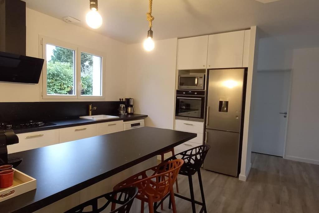 eine Küche mit schwarzer Arbeitsplatte und Kühlschrank in der Unterkunft Villa d'Orée, Bordeaux Saint-Aubin-de-Médoc in Saint-Aubin-de-Médoc