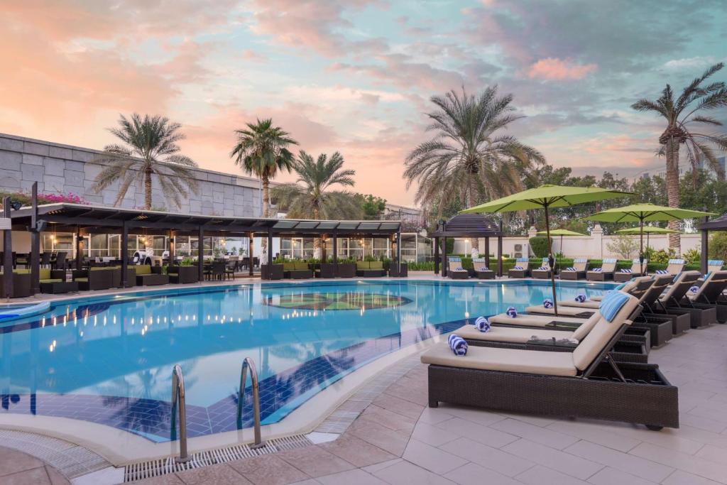 una grande piscina con lettini e ombrelloni di Radisson Blu Hotel, Muscat a Mascate