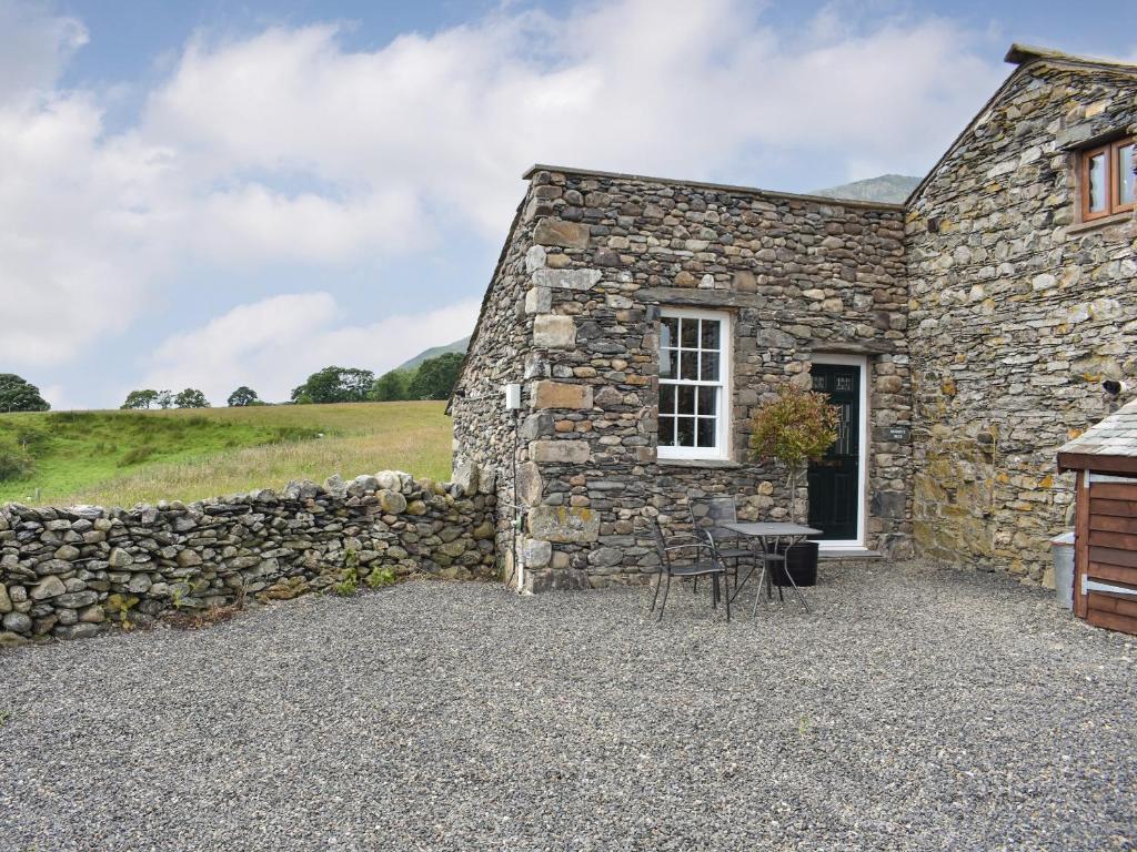 a stone house with a table and a stone wall at Doddick Beck - Uk39153 in Threlkeld