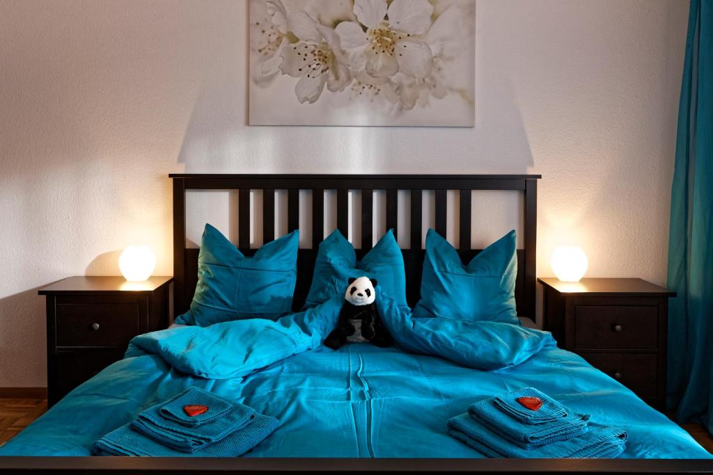 a bedroom with a bed with blue pillows and a panda at Max Aviation Villa & Apartments in Bern