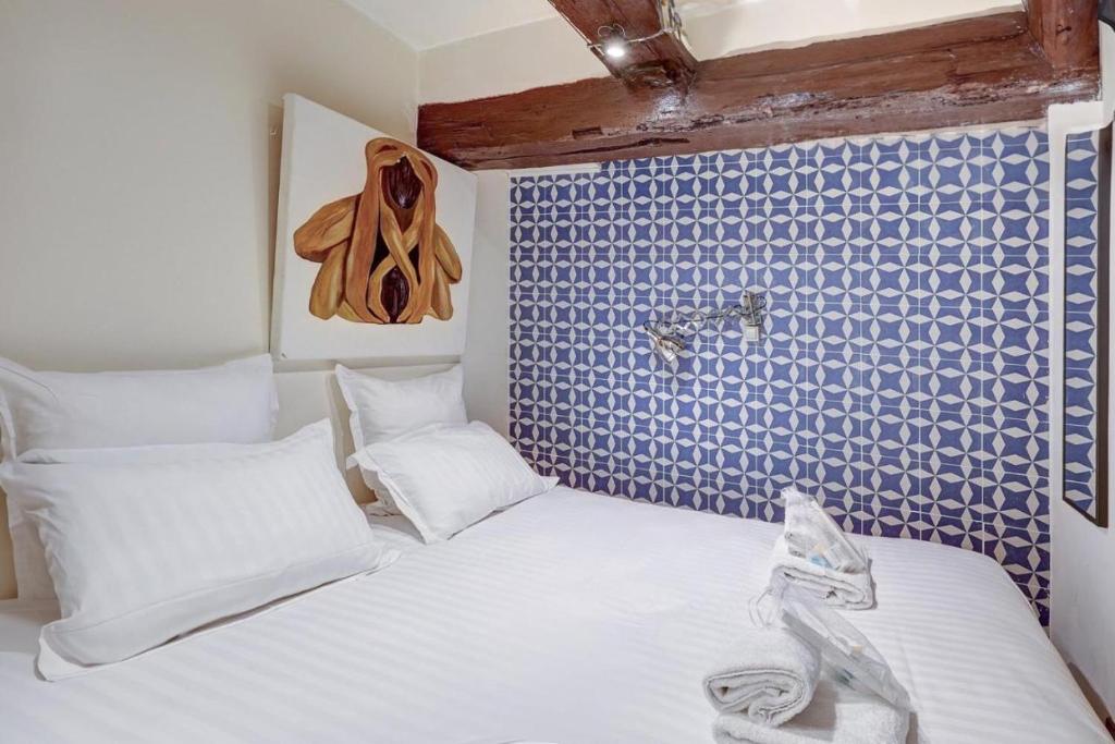 une chambre avec un lit blanc avec un mur bleu dans l'établissement Paris Maison Lombards Terrasse, à Paris