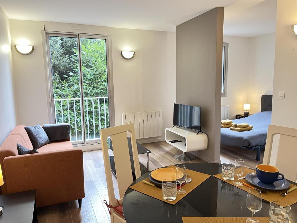 - un salon avec un canapé, une table et une télévision dans l'établissement L'Horizon - Parking - Wi-Fi - 2 pers, au Mans