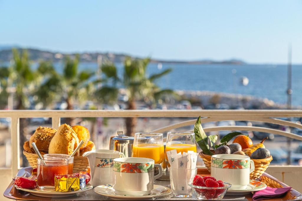 Una bandeja con comida para el desayuno sobre una mesa junto a la playa en Hotel de la Baie, en Bandol