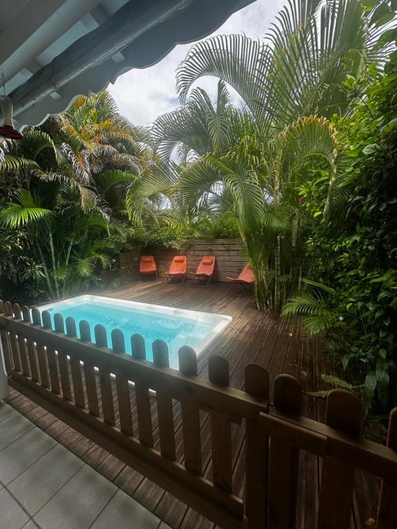 a swimming pool on a deck with chairs and palm trees at Villa Ti Gîte - Piscine privée in Le Marin