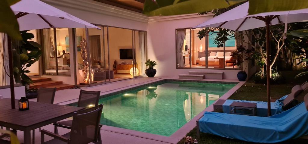 - une piscine avec des chaises, une table et un parasol dans l'établissement Luxury 3 bedroom pool villa, à Laguna Phuket