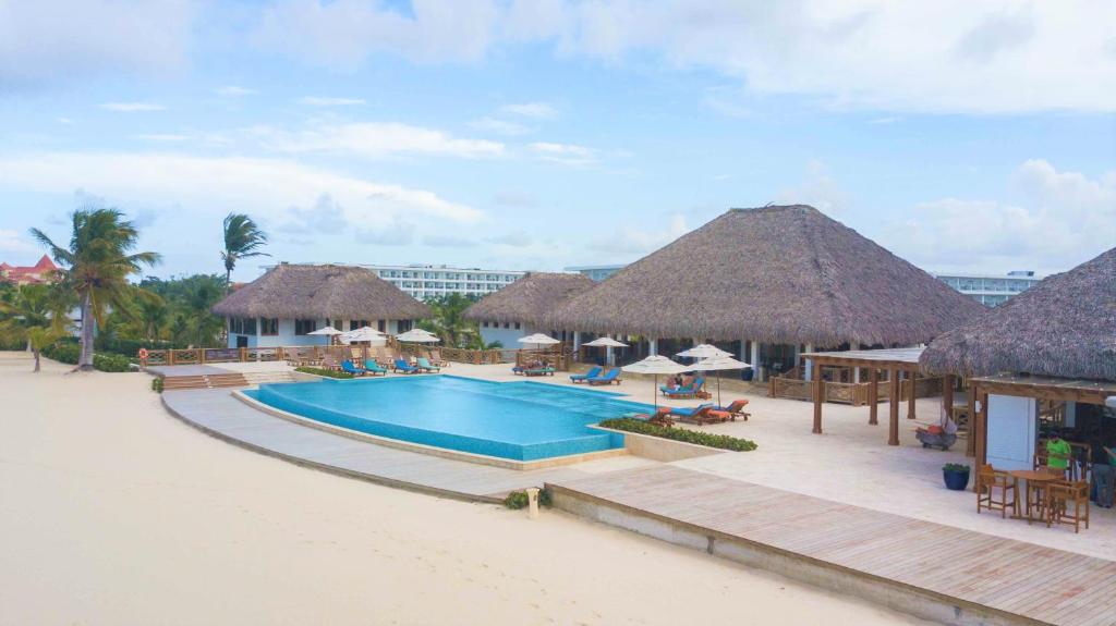 a resort with a swimming pool and straw huts at Cana Rock in Punta Cana