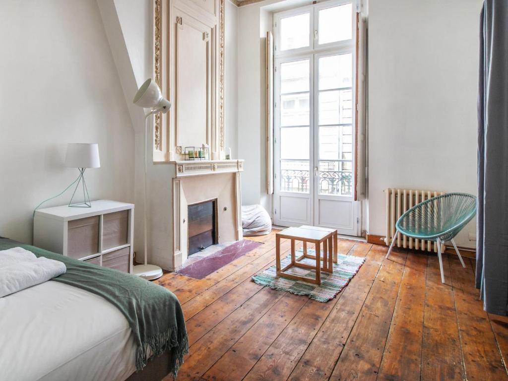 - une chambre avec un lit, une cheminée et une chaise dans l'établissement Rolland, à Bordeaux