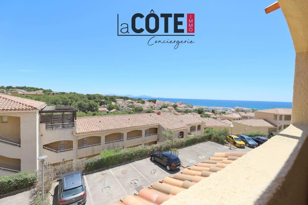 - une vue sur un bâtiment avec des voitures garées dans un parking dans l'établissement Le Madura, à Sausset-les-Pins