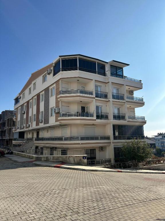 a tall apartment building with balconies on a street at Mavi Restaurant & Apartments 2 in Didim