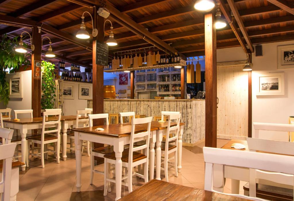 a restaurant with wooden tables and white chairs at Hotel La Villa Del Mare in Cagliari
