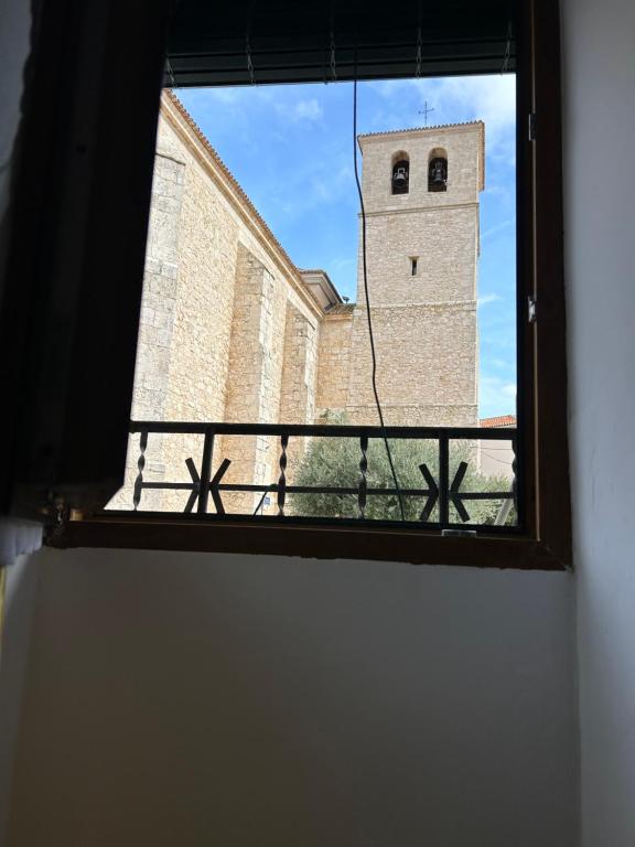 a window view of a building with a clock tower at La Bodeguita in Belmonte de Tajo