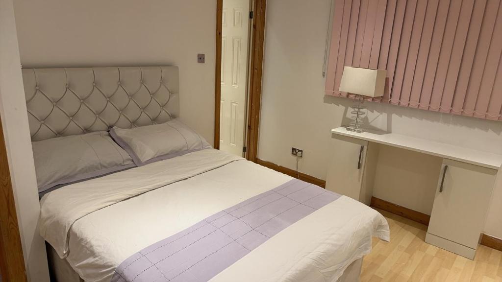 1 dormitorio con cama blanca y cabecero de plata en Raeburn Avenue House, en Worcester Park