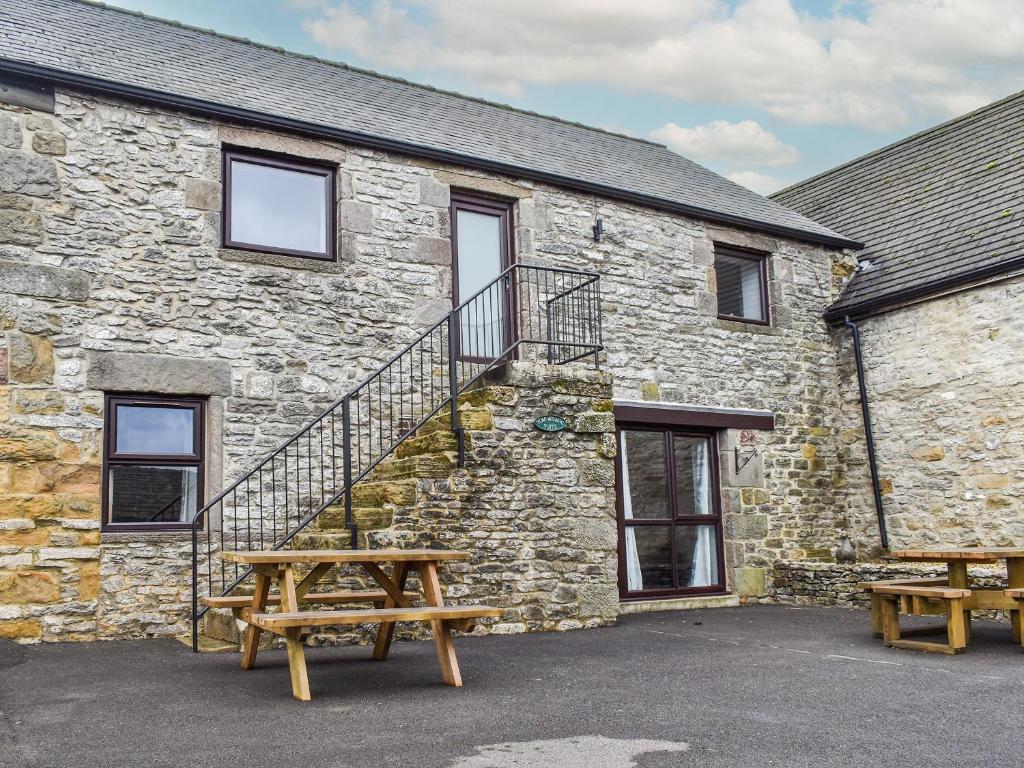 ベイクウェルにあるTom Wragg Suite - Uk40248の石造りの建物で、その前にピクニックテーブルが2台あります。