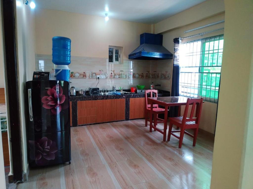 Una cocina con refrigerador y una mesa con sillas. en Pokhara Apartment CS, en Pokhara
