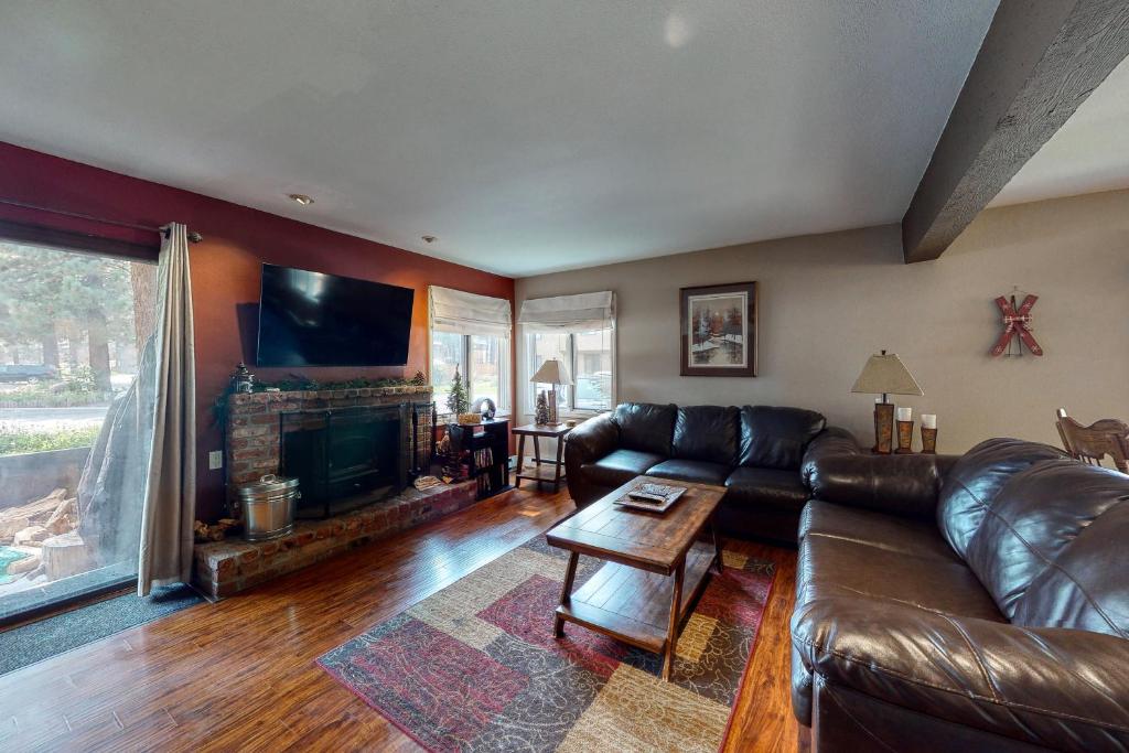 Una sala de estar con un sofá de cuero y una chimenea. en Wildflower 47, en Mammoth Lakes