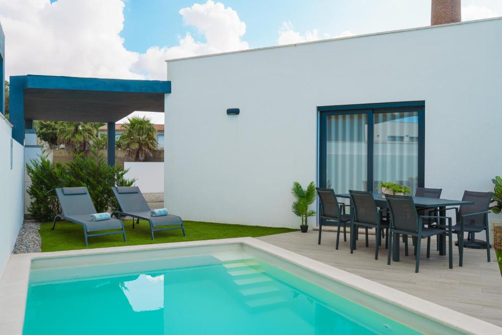 eine Terrasse mit Tisch und Stühlen neben einem Swimmingpool in der Unterkunft Villa Lola in Mariquiteira