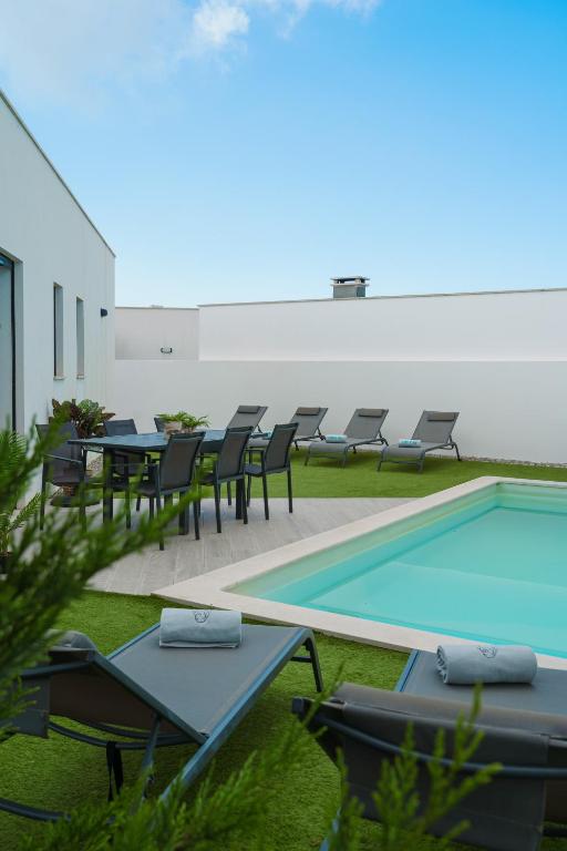 eine Terrasse mit Tischen und Stühlen neben einem Pool in der Unterkunft Villa Lola in Mariquiteira