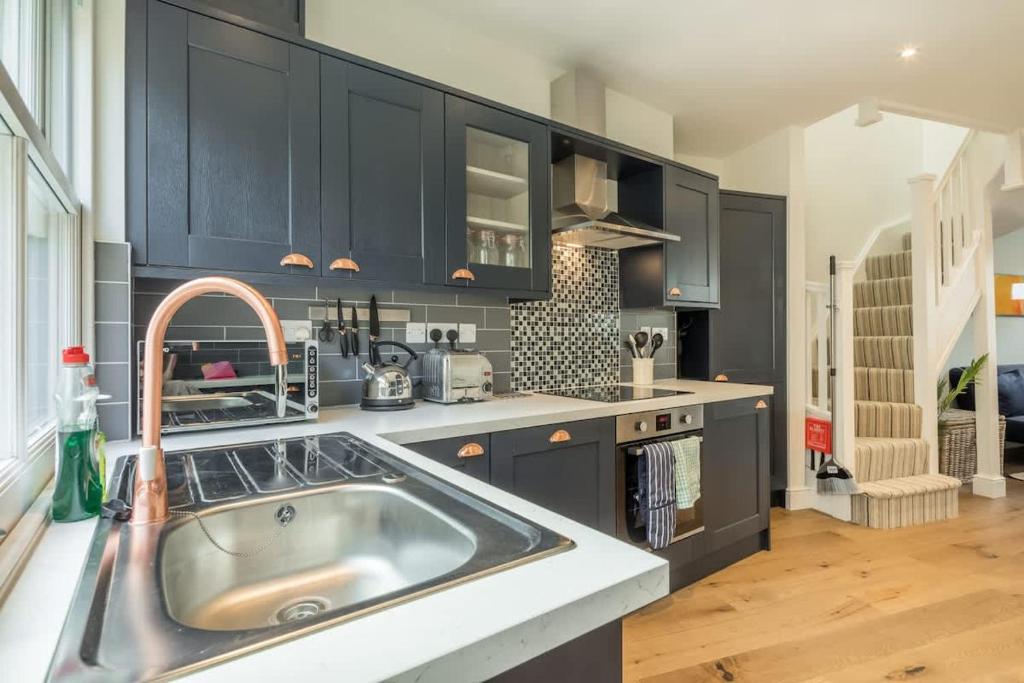 a kitchen with black cabinets and a sink at Beautiful 2bed Central Home in Cambridge