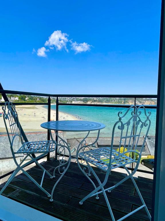 une table et des chaises sur un balcon avec la plage dans l'établissement Un Balcon sur la Mer, à Crozon