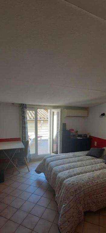 une chambre avec un grand lit et une grande fenêtre dans l'établissement Chambre ,terrasse, a dames exclusivement women only, à Narbonne