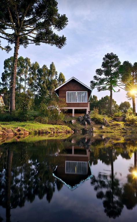 a house with a pond in front of it at Chalé do Lago Urupema SC in Urupema