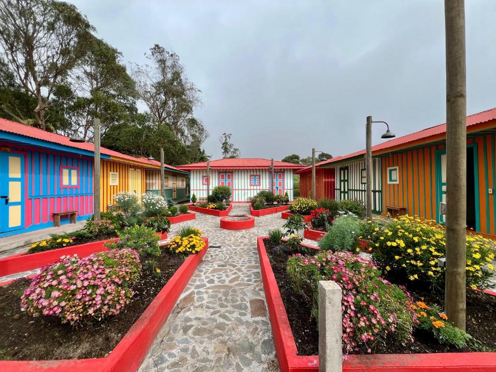 a row of colorful buildings with flowers and plants at El Agrado Restaurante Cabañas in Líbano
